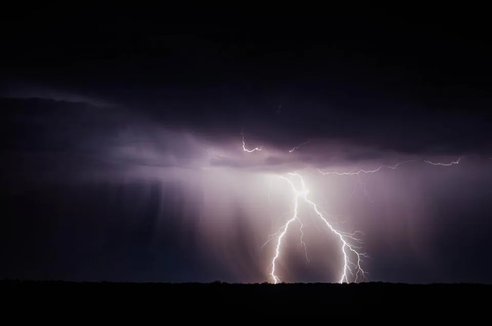 Lightning over a dark landscape at night